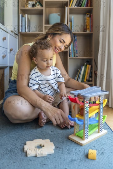 Smiling mother and son playing with a toy car and garage, enjoying quality time together in their