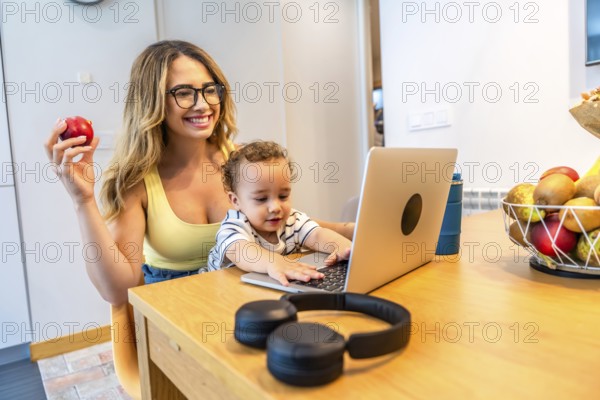 Happy mother working from home, eating healthy and taking care of her baby, while her son is