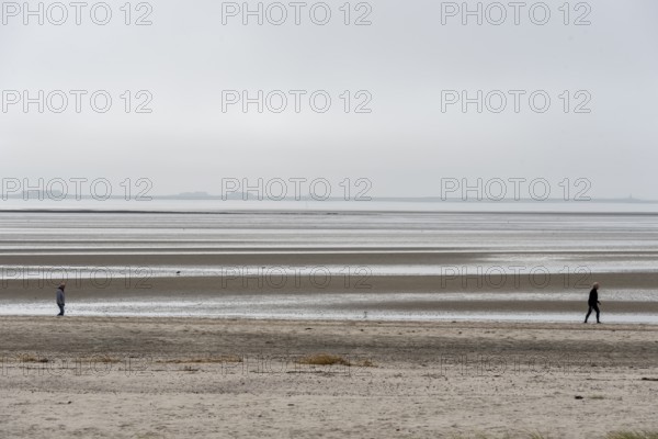 Two people walking on the wide beach of the island of Föhr, Schleswig-Holstein, Germany, at low