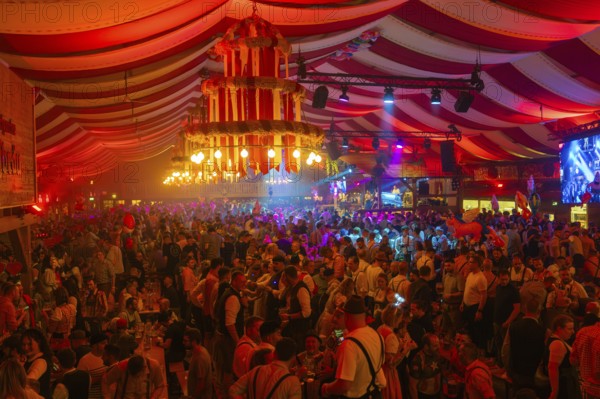 Lively and colourful celebration in a large beer tent full of people and bright decorations,