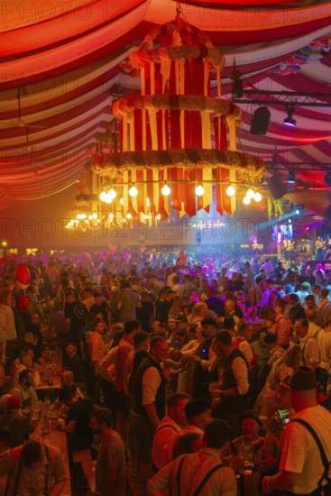 Large crowd celebrates in the festive light of a beautifully decorated marquee, Cannstatter Wasen