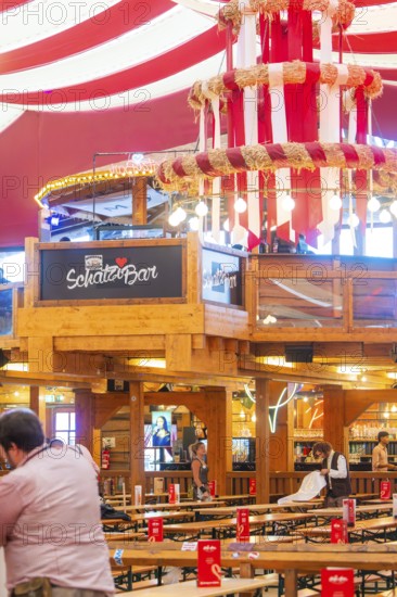 Bar area in a festively decorated beer tent with red ceilings and wooden elements, Volksfest