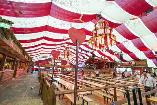 Cosy beer tent with red blankets, wooden benches and hearts as decoration, Volksfest Cannstatter