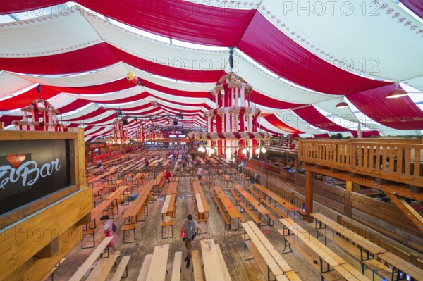 Marquee with red ceilings and wooden benches, bar in the foreground, inviting atmosphere,