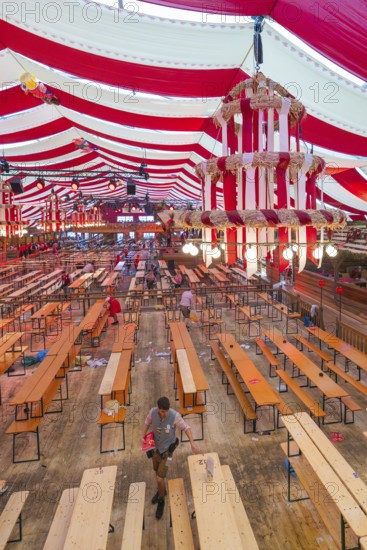 View of a festively decorated beer tent with red blankets and empty wooden benches, Volksfest