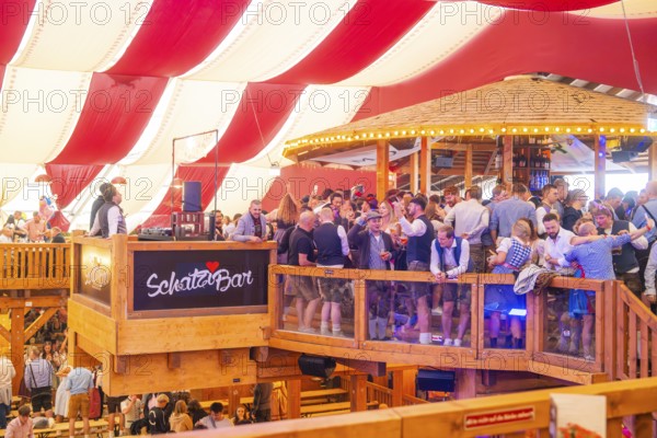A crowded upper bar with people in traditional dress in a festively decorated room, Volksfest