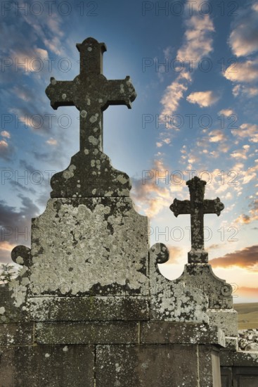 Two weathered crosses stand tall against a colorful sunset sky, showcasing the beauty of an ancient