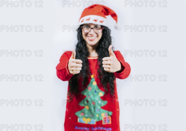 Young woman in Christmas sweater gesturing Ok with thumbs up. isolated. Smiling girl in Christmas