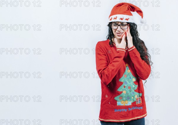 Girl in Christmas dress with toothache on isolated background. Young girl with toothache holding
