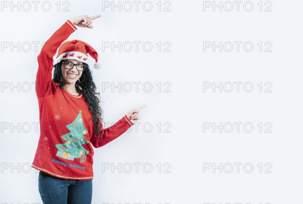 Smiling girl in Christmas sweater pointing to the side, isolated. Happy young woman in Christmas
