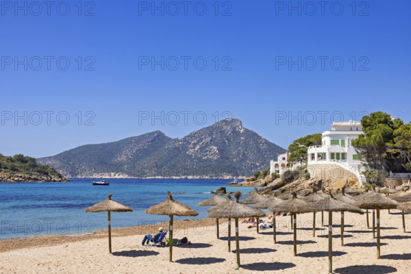 Sandy beach on the Mediterranean Sea with sun umbrellas and houses along the coast on a sunny