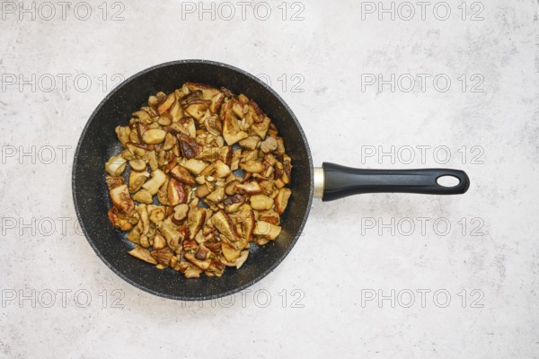 Diced porcini mushrooms are frying in a black pan, creating a savory meal. The cooking process
