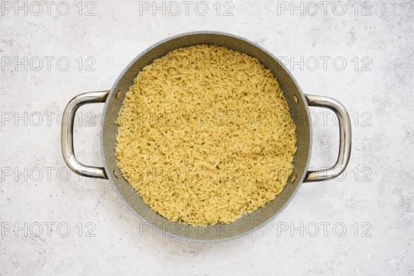 A pot filled with perfectly cooked risoni pasta on a neutral surface. This dish showcases a rich