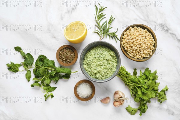 Various fresh herbs and ingredients are neatly organized on a marble surface, ready for sauce