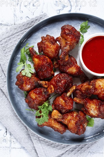 Crispy pieces of fried chicken, on a plate with sauce and herbs, in a modern kitchen environment,