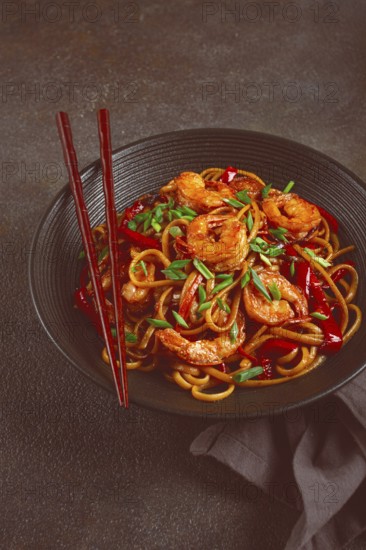 Udon stir-fry shrimp noodles with red bell pepper and green onion, served in a black bowl, with