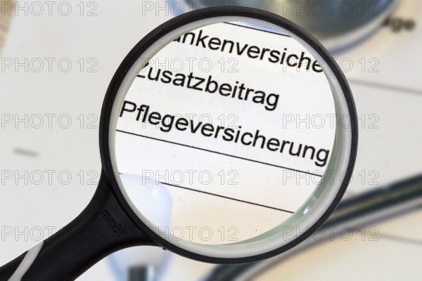 (Photomontage) Close-up of the word PFLEGEVERSICHERUNG on a document, enlarged with a magnifying