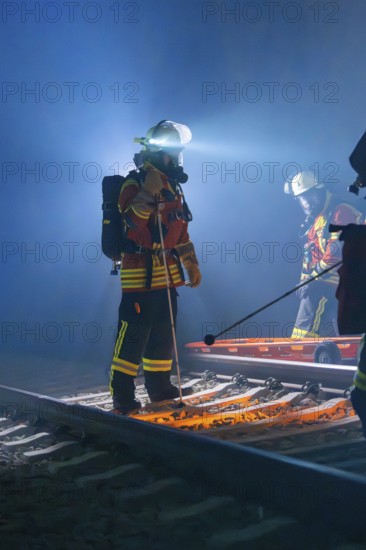 Rescue workers at work on tracks with stretcher and helmet in the dark, fire brigade exercise in