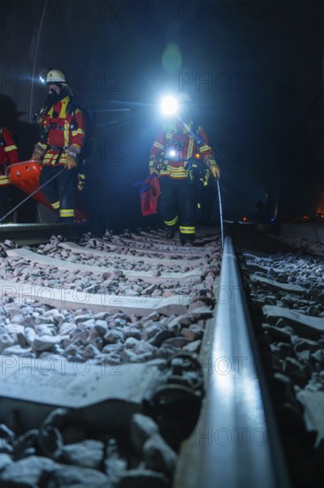 Firefighters on rails, the surroundings illuminated by emergency lighting, firefighting exercise in