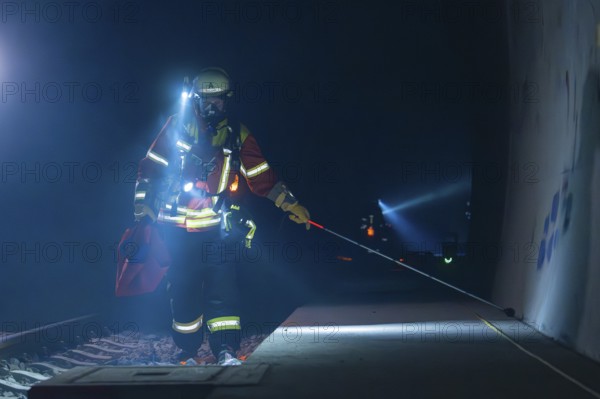 Fireman on a railway platform, at work in the evening with a torch, fire drill in the new