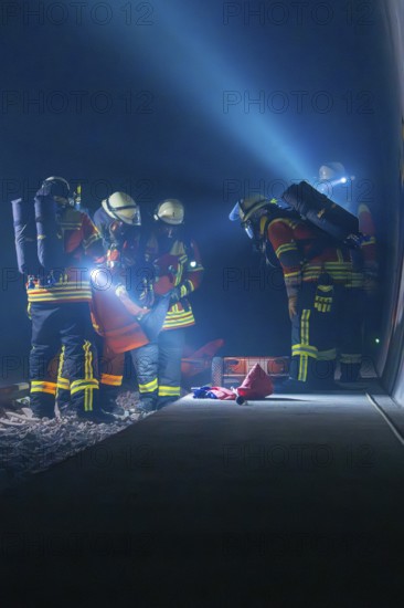 Firefighters working on the tracks at night, illuminated by helmet lamps, firefighting exercise in