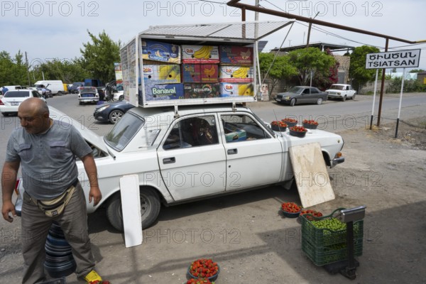 A car as an improvised roadside fruit market stall, selling fruit such as strawberries by the