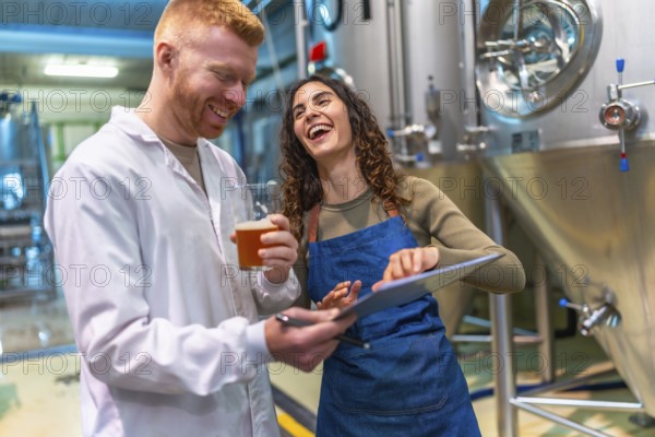 Man and woman tasting and checking craft beer quality, smiling and laughing together while