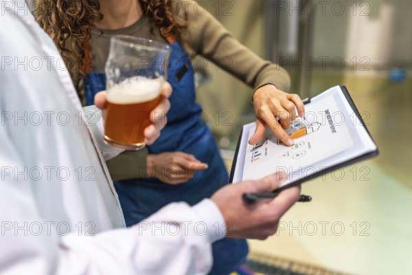 Brewery staff discussing quality control data and production metrics from a clipboard report while