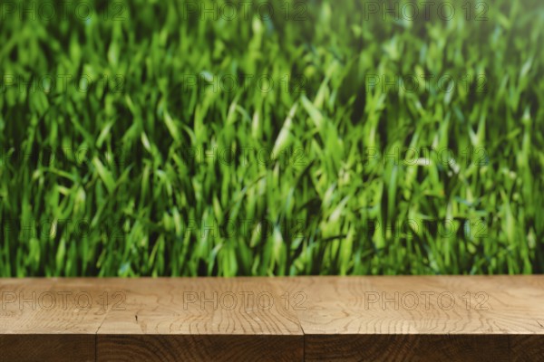 A wooden tabletop is placed in front of a lush green grass background. Sunlight enhances the vivid