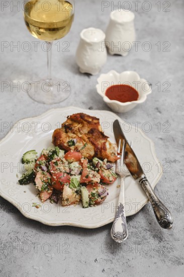 A well-prepared meal features grilled chicken, fresh salad with tomatoes and cucumbers, and a glass