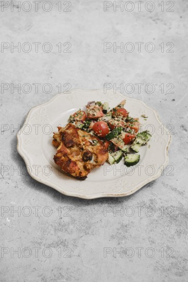 A delightful meal features a colorful salad with tomatoes and cucumbers placed beside a savory