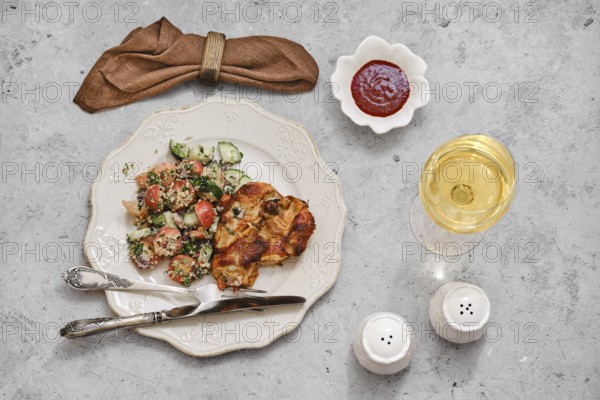 A beautifully arranged meal features grilled chicken with a side of vibrant salad made of tomatoes