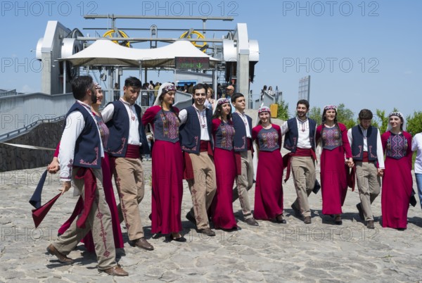 Group performing traditional dance on paved area in sunny weather, folklore, Tatev, Tatev, Syunik