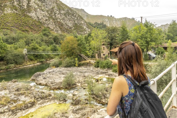 Tourist with a backpack pointing at the olla de san vicente, a natural pool on the sella river,