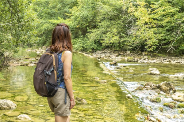 Female tourist with a backpack admiring the dobra river along the hiking route to olla de san