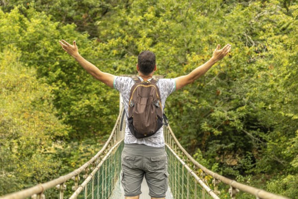 Backpacker opening his arms while enjoying the view from a hanging bridge over the sella river,