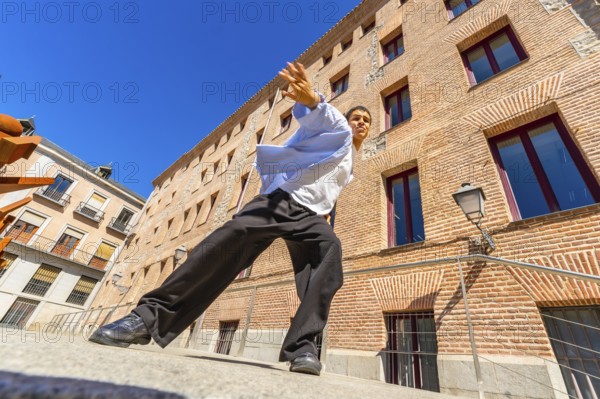 Young man actively performing a passionate flamenco move on a city street, expressing cultural