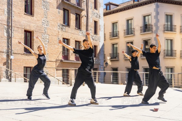 Group of diverse urban dancers performing synchronized street dance movements with raised arms and