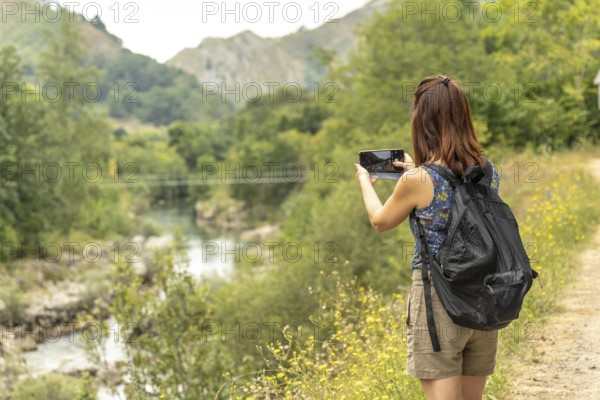 Female tourist with a backpack capturing photos of the dobra river along the scenic route to olla