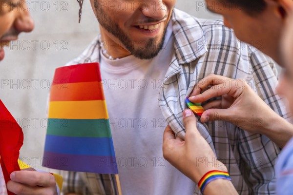 Happy man smiles as someone pins a rainbow flag badge to his plaid shirt, celebrating lgbtq pride,