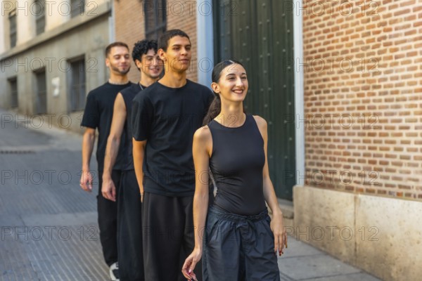 Young diverse dancers walking in line down a city street, smiling and energized while rehearsing