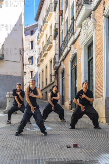 Group of four young dancers expressing movement and energy through a choreographed street