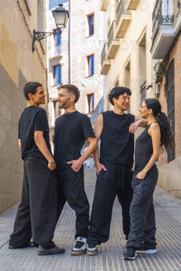 Four diverse young friends wearing black casual clothing are happily interacting, smiling, and
