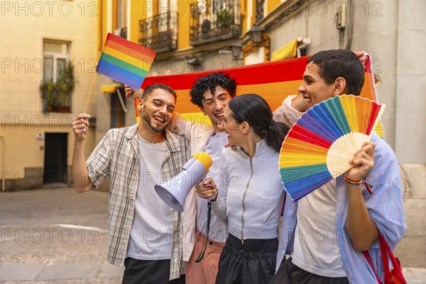 Group of diverse young adults laughing and holding a rainbow flag, a small rainbow flag, a rainbow