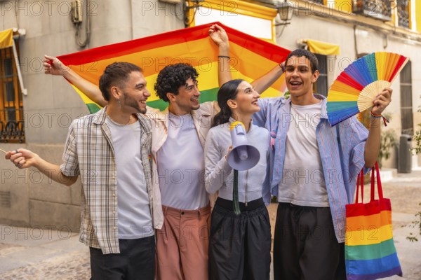 Diverse group of young adult friends smiling and holding a rainbow flag, fan, megaphone, and tote