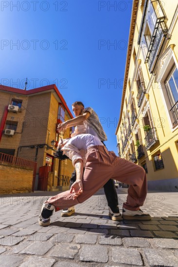 Two skilled dancers engaging in a passionate contemporary performance on a cobblestone street,