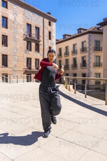 Young woman dancer performing dynamic contemporary routine on a sunny city street, showcasing urban