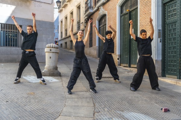 Four young dancers perform synchronized street choreography on an urban street, radiating energy,