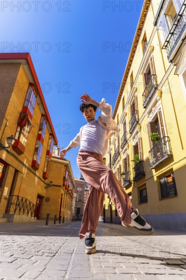 Young man dancer performing a dynamic street dance move in a vibrant old city urban setting under a