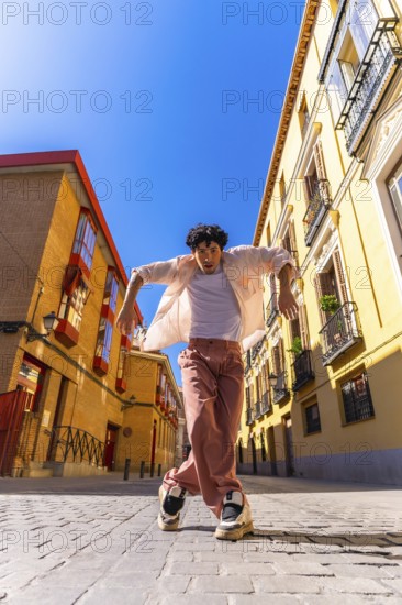 Stylish young man with intense expression executing a dynamic street dance move on cobblestones in